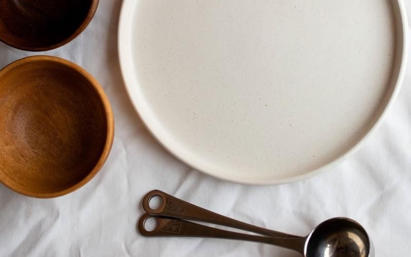 bowls, a plate and measuring spoons arranged neatly on cloth